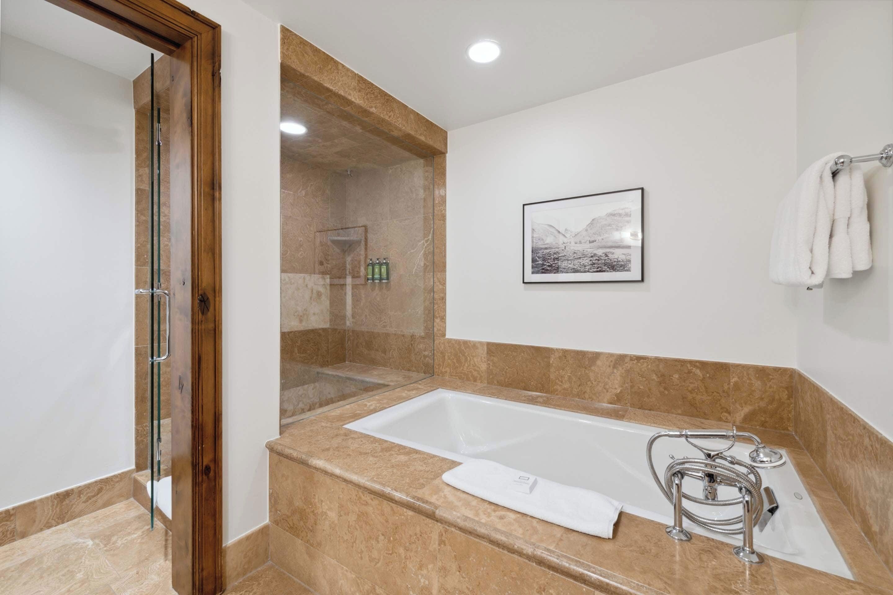 A modern bathroom with a large bathtub, a glass shower enclosure, and a framed picture on the wall.
