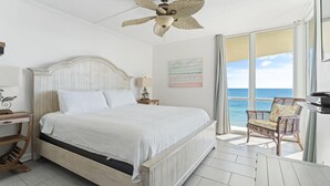 A bedroom with a bed, a ceiling fan, a nightstand, a chair, and a view of the ocean. - Perdido Sun 916 (Pensacola)
