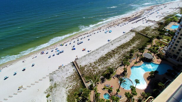 A beach resort with a swimming pool, beach umbrellas, and a view of the ocean. - Indigo East 2001 (Pensacola)