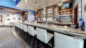 A bar area with a long counter, multiple bar stools, and a variety of bottles and glasses on shelves. - Amalz # 5, MGM Signature 2 Bedroom Balcony Suites ! (Las Vegas)