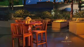 An outdoor dining area with tables and chairs, string lights, and plants. - Amalz # 5, MGM Signature 2 Bedroom Balcony Suites ! (Las Vegas)