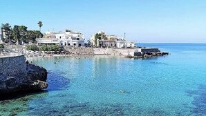Un pueblo costero con aguas azul turquesa, costa rocosa y edificios a lo largo de la línea de costa.
