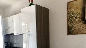 Una cocina moderna con armarios blancos y un sofá gris en una sala de estar.