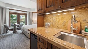 Habitación de hotel con cocina, que incluye un fregadero, armarios y una mesa de comedor con sillas.