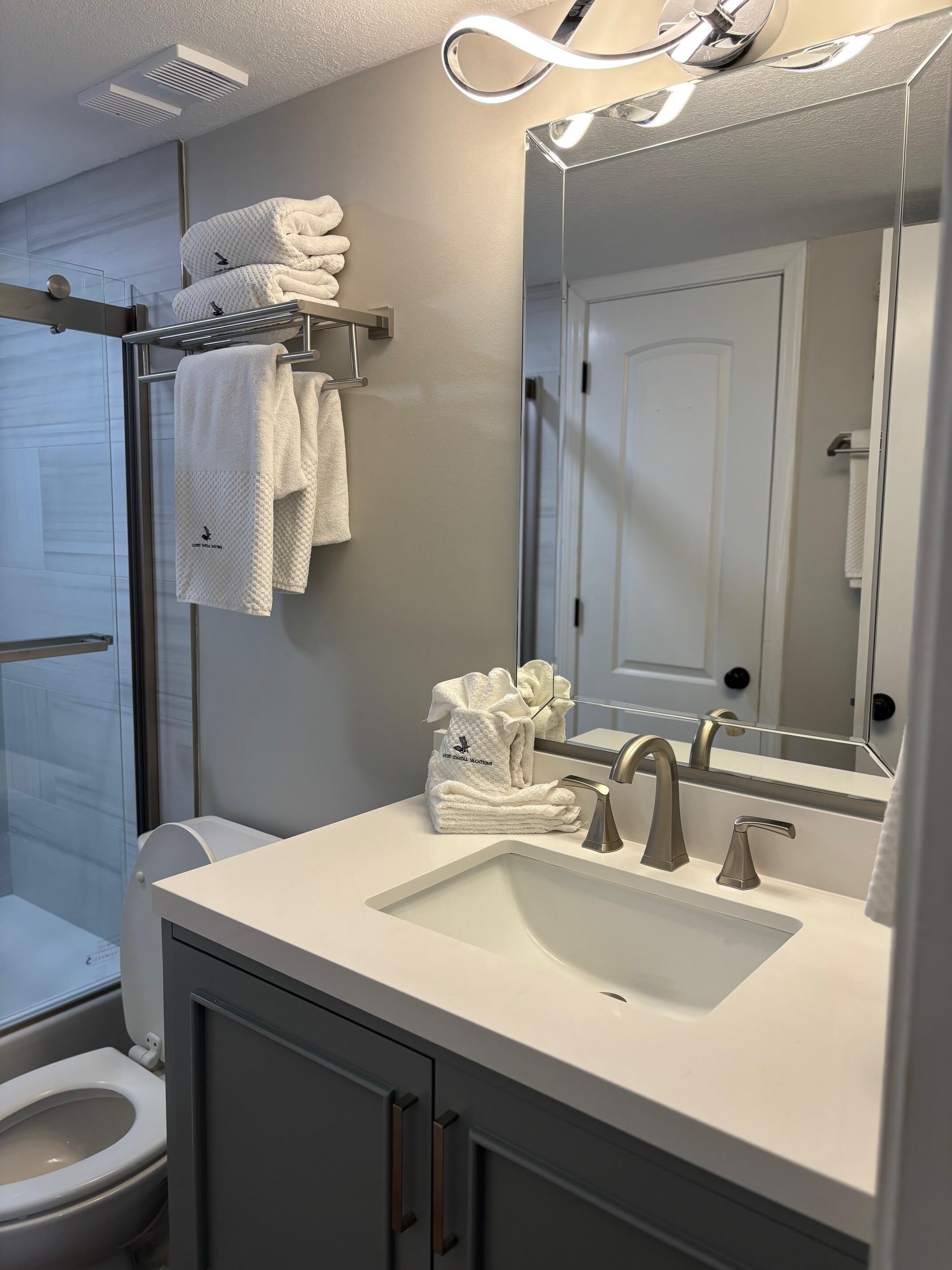 Une salle de bain moderne avec un lavabo blanc, un miroir et un porte-serviettes.