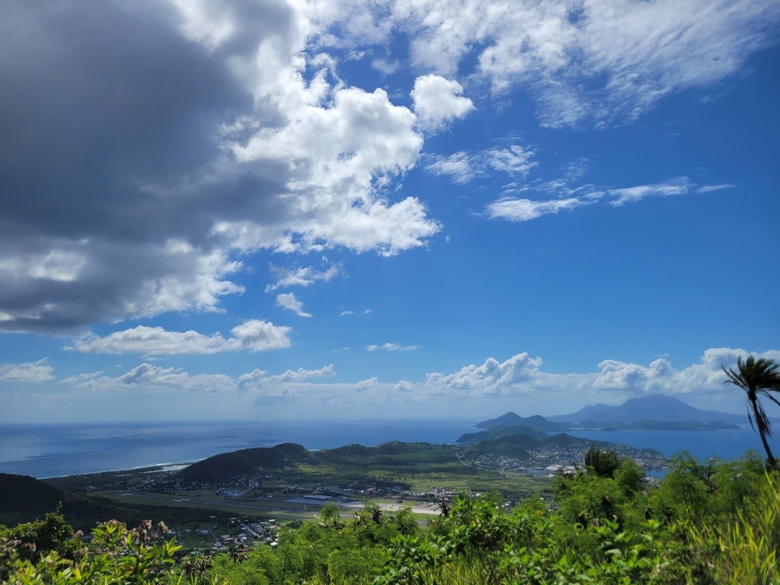 Un paysage côtier offrant une vue sur l’océan, les montagnes et une ville.