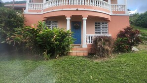 A two-story house with a balcony, a blue door, and a well-maintained lawn.