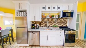 A compact kitchen with white cabinets, a stainless steel refrigerator, a microwave, and a stove.