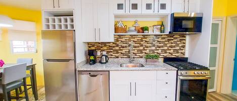 A compact kitchen with white cabinets, a stainless steel refrigerator, a microwave, and a stove.