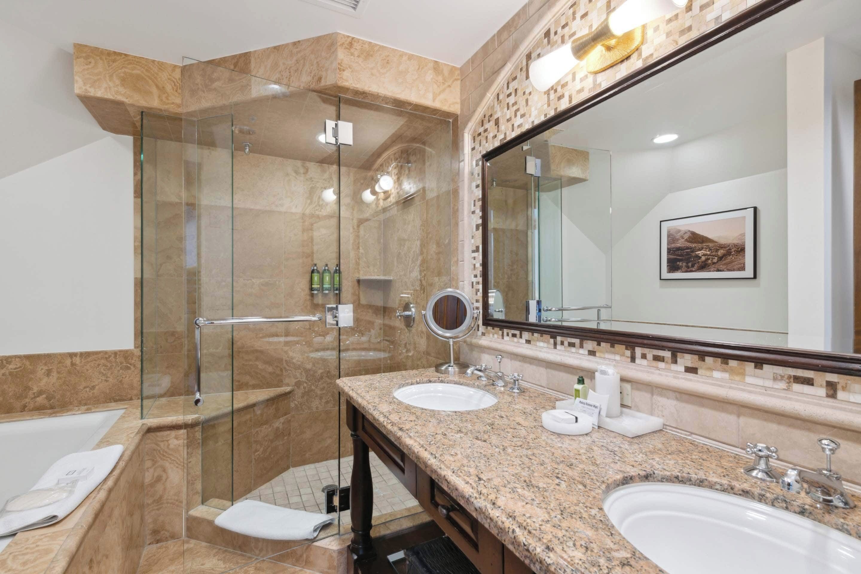 A modern bathroom with a glass-enclosed shower, two sinks, and a large mirror.
