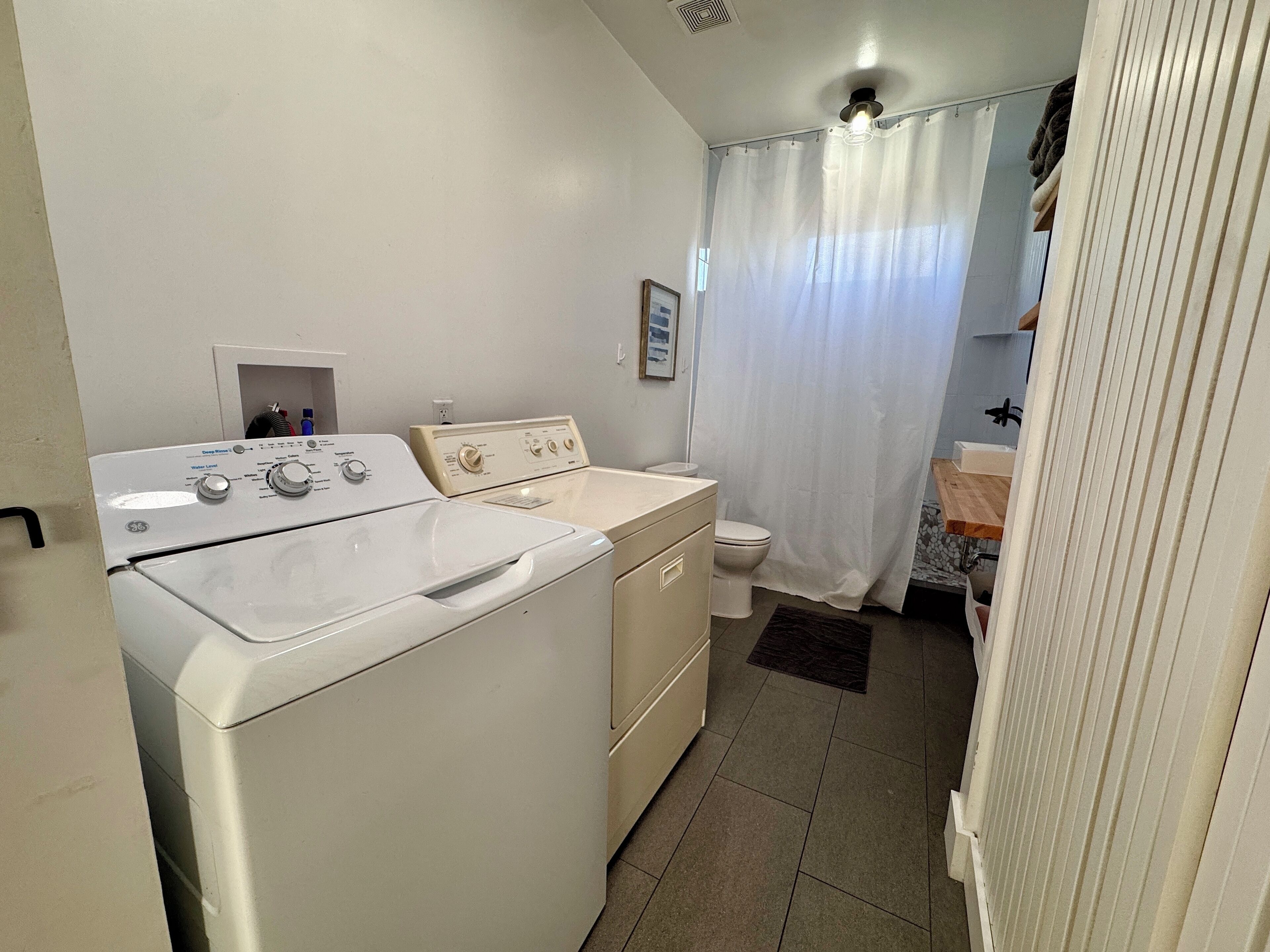 A compact bathroom with a washing machine, a toilet, and a sink.
