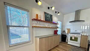 Une cuisine moderne avec des meubles en bois, un four encastré et une fenêtre équipée de stores.