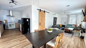 Une cuisine moderne avec un coin repas, un réfrigérateur noir et une table à manger en bois avec des chaises.
