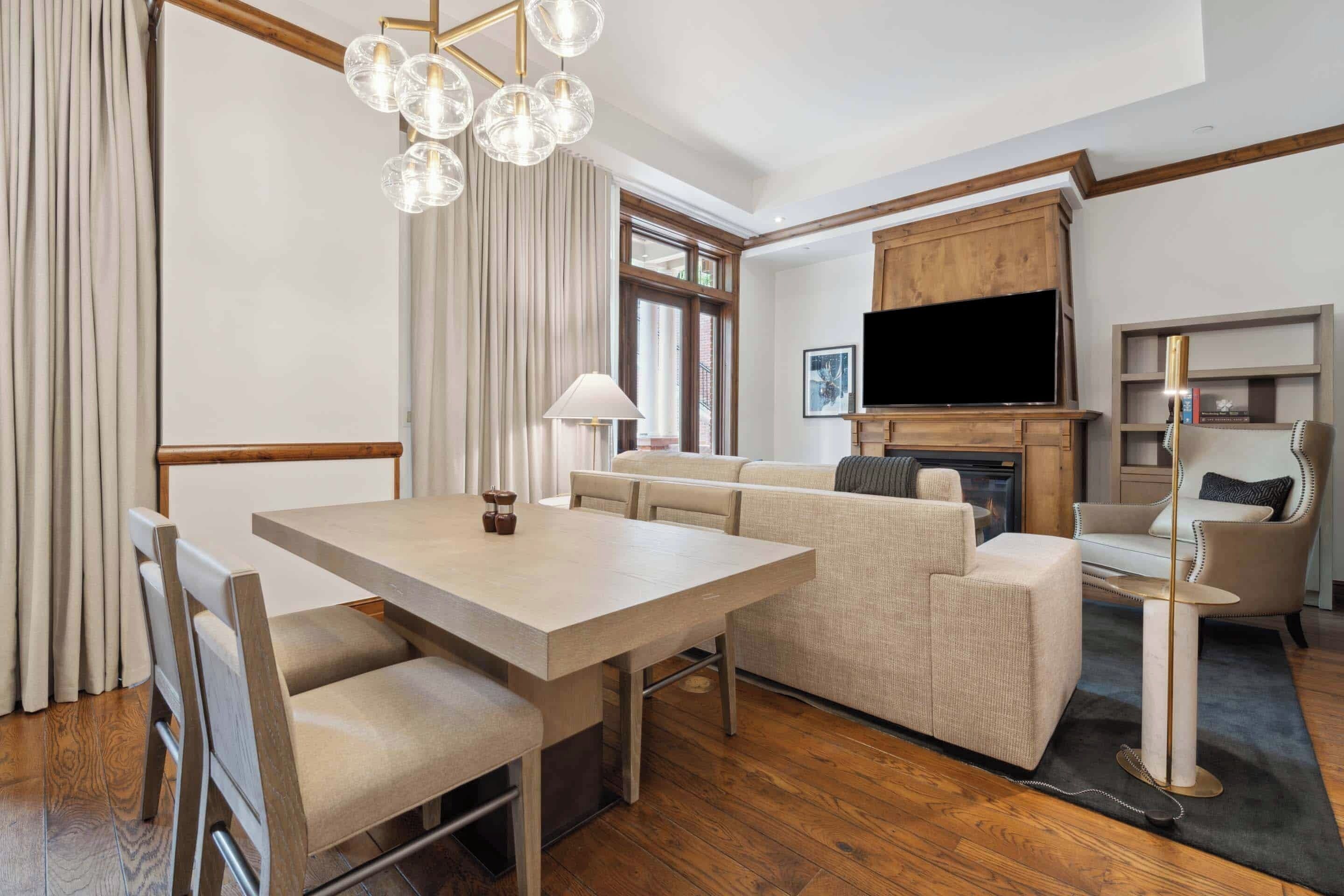 A modern living room with a dining area, a sofa set, a TV, and a fireplace.