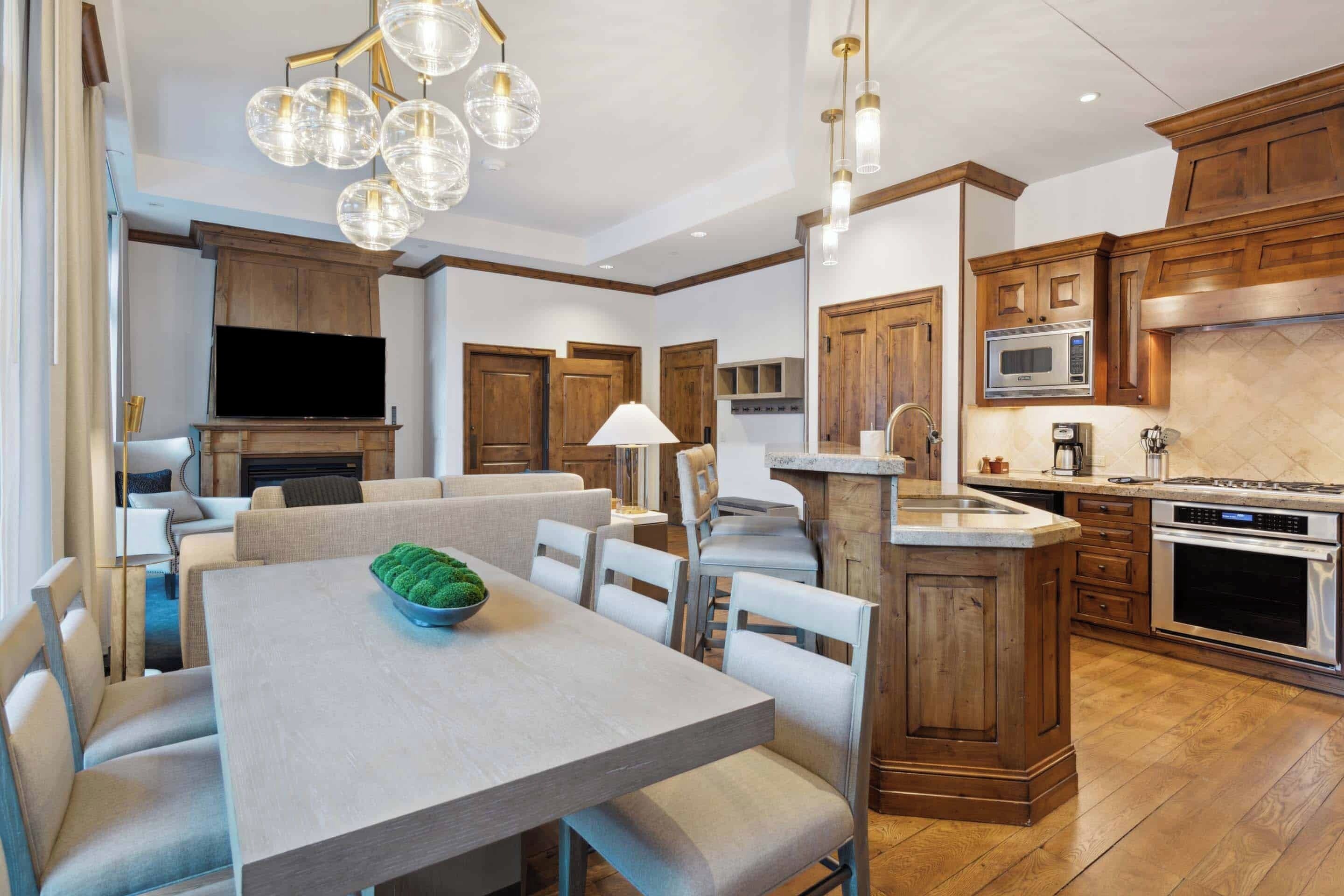 Una cocina moderna con armarios de madera, una isla central y una zona de comedor con mesa y sillas.