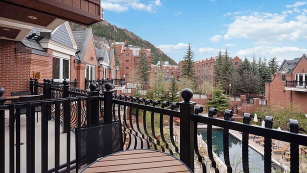 A balcony with a wooden deck overlooking a pool and a mountainous landscape. - The Aspen Mountain Residences 38A - Studio Residence (Aspen)