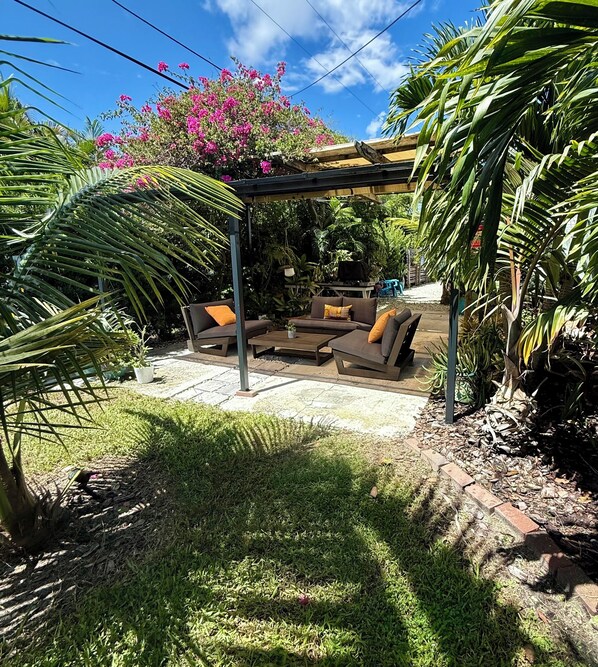 An outdoor patio area with a pergola, two sofas with cushions, and a small table. - Shady Acres Owner’s Suite (Stuart)