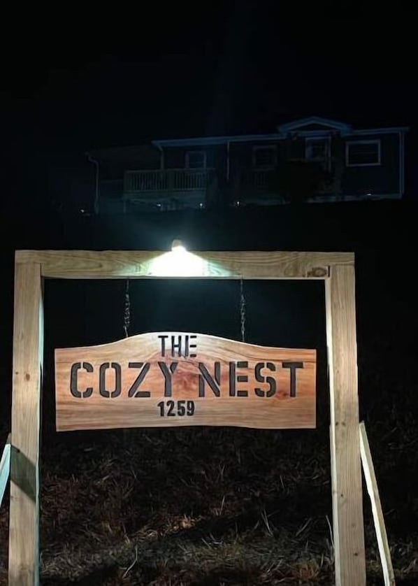 Welcome to The Cozy Nest, a charming lodging with a simple wooden sign.