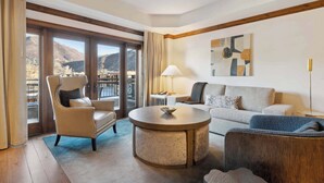 Una habitación de hotel moderna con un balcón grande, una mesa de centro redonda, un sofá y una silla.