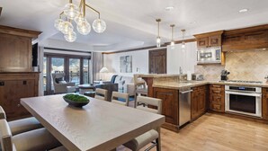 Una cocina moderna con armarios de madera, una isla central y una zona de comedor con una mesa y sillas.