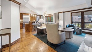 A modern kitchen with wooden cabinets and stainless steel appliances, a dining area with a round table and chairs, and large windows offering views of the outside.