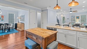 Une cuisine spacieuse avec des meubles blancs, un îlot central en bois et des luminaires suspendus.