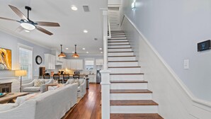 Un salon moderne avec un escalier, un plancher en bois et un ventilateur de plafond.