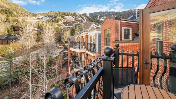 Un edificio residencial con balcón, fachada de ladrillo y vistas a un paisaje montañoso.