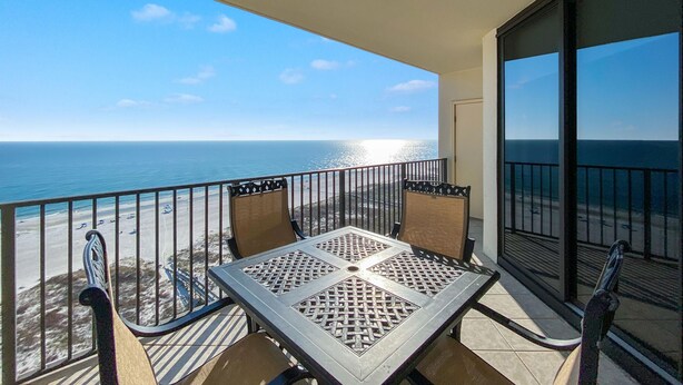A balcony with a table and chairs, overlooking a beach and the ocean. - Phoenix Viii 1506 (Orange Beach)