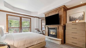 Une chambre à coucher avec un grand lit, une cheminée, un téléviseur et une commode en bois.