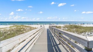 A wooden boardwalk leading to a beach with sand dunes and a clear blue sky. - Seaspray West 503- Gulf Front (Pensacola)