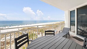 A balcony with a view of the beach, a table, and two chairs. - Seaspray West 503- Gulf Front (Pensacola)