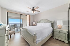 A bedroom with a bed, bedside tables, a ceiling fan, and a view of the balcony. - White Caps 603 (Orange Beach)