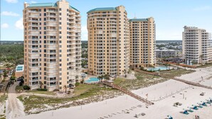 A beachfront hotel with multiple high-rise buildings, a sandy beach, and a pool area. - Beach Colony East 7A (Pensacola)