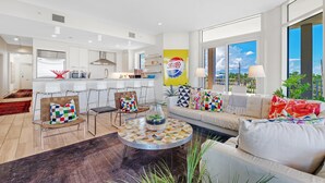 A modern living room with a sofa, chairs, a coffee table, and a view of the outdoors. - Vista Del Mar 201 (Pensacola)