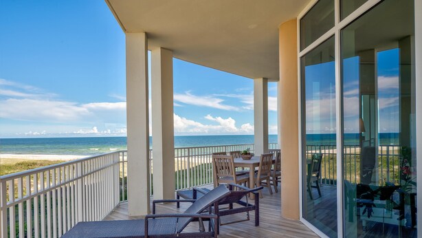 A balcony with a view of the ocean, furnished with lounge chairs and a table. - Vista Del Mar 201 (Pensacola)