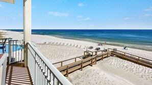 Blick auf einen Strand vom Balkon aus, mit Holzboden, Sandstrand und Meer.