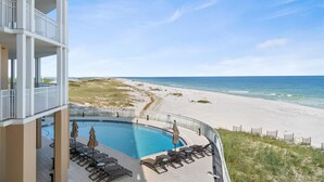 Blick auf einen Pool mit Strand und Ozean im Hintergrund.