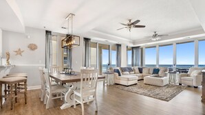 A spacious living room with a wooden dining table, white chairs, a large sofa, and a ceiling fan. - La Playa 301 (Pensacola)