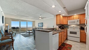 A spacious living area with a kitchen, wooden cabinets, a microwave, and a dishwasher. - Perdido Sun 712 (Pensacola)