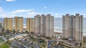 A high-rise hotel with multiple floors, a parking area, and a pool.
