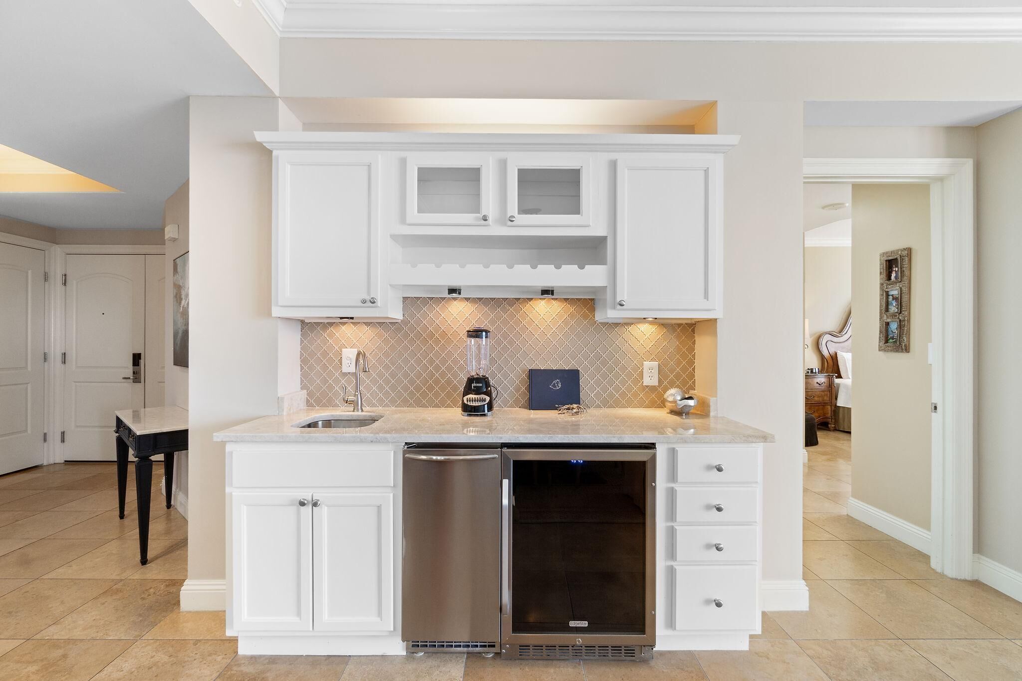 A modern kitchen with white cabinetry, a built-in dishwasher, and a countertop with a blender.