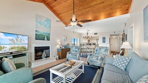A spacious living room with a large TV, comfortable seating, a fireplace, and a view of the ocean. - Shipwatch A804 (Pensacola)