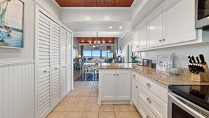 A kitchen with white cabinets, a granite countertop, and a wooden ceiling. - Shipwatch A804 (Pensacola)