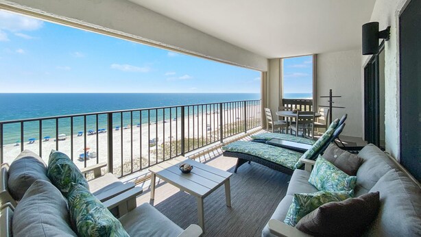 A balcony with a view of the beach and ocean. There is a sofa, a small table, and a chair. - Shipwatch A804 (Pensacola)
