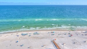 A beach with clear blue water, sandy shore, and umbrellas. - Beach Colony East 16b-penthouse (Pensacola)