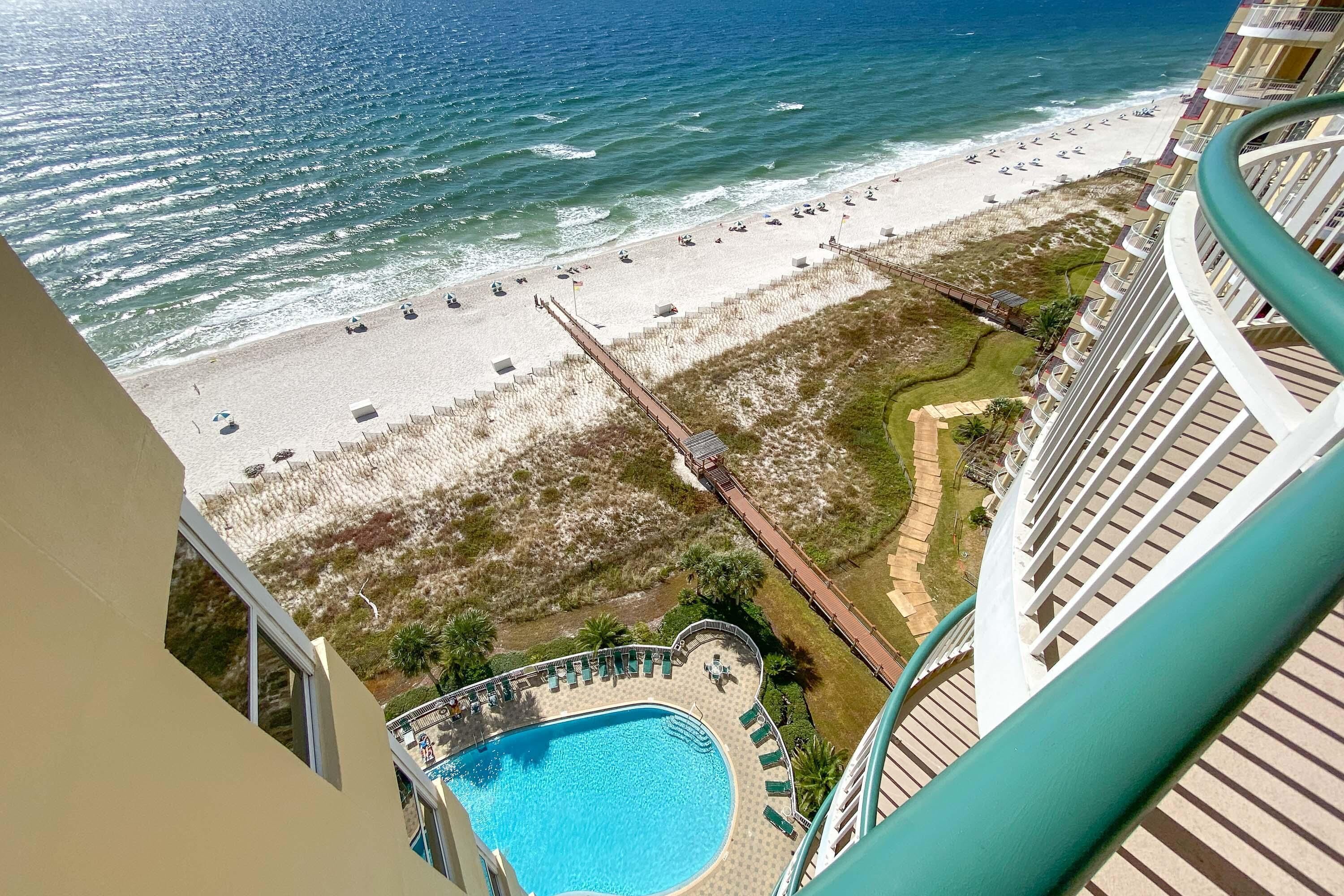 A high-rise hotel with a view of a beach and a swimming pool.