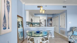 A modern kitchen with white cabinets, a glass dining table, and a blue bowl centerpiece. - Tidewater 706 (Orange Beach)