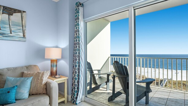 A balcony with a view of the beach, a sofa with cushions, a lamp, and a painting on the wall. - Tidewater 706 (Orange Beach)