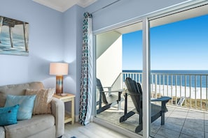 A balcony with a view of the beach, a sofa with cushions, a lamp, and a painting on the wall. - Tidewater 706 (Orange Beach)